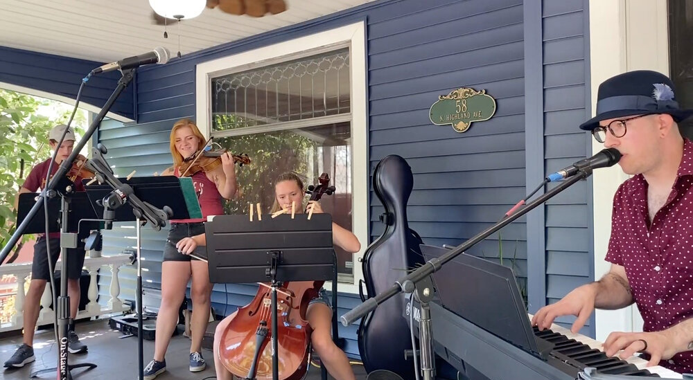 Jeff Klemm and a string quartet perform on a porch.